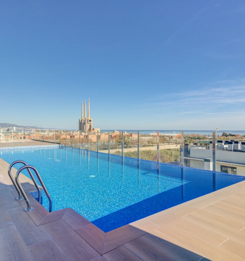 Piscina exterior en la azotea, barandilla de seguridad de cristal, escalera metálica y vistas a la ciudad.