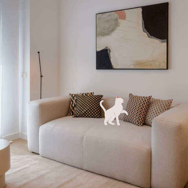 Un salón moderno con un sofá beige, cojines estampados, arte abstracto en la pared y una ilustración de un gato blanco sobre el sofá.